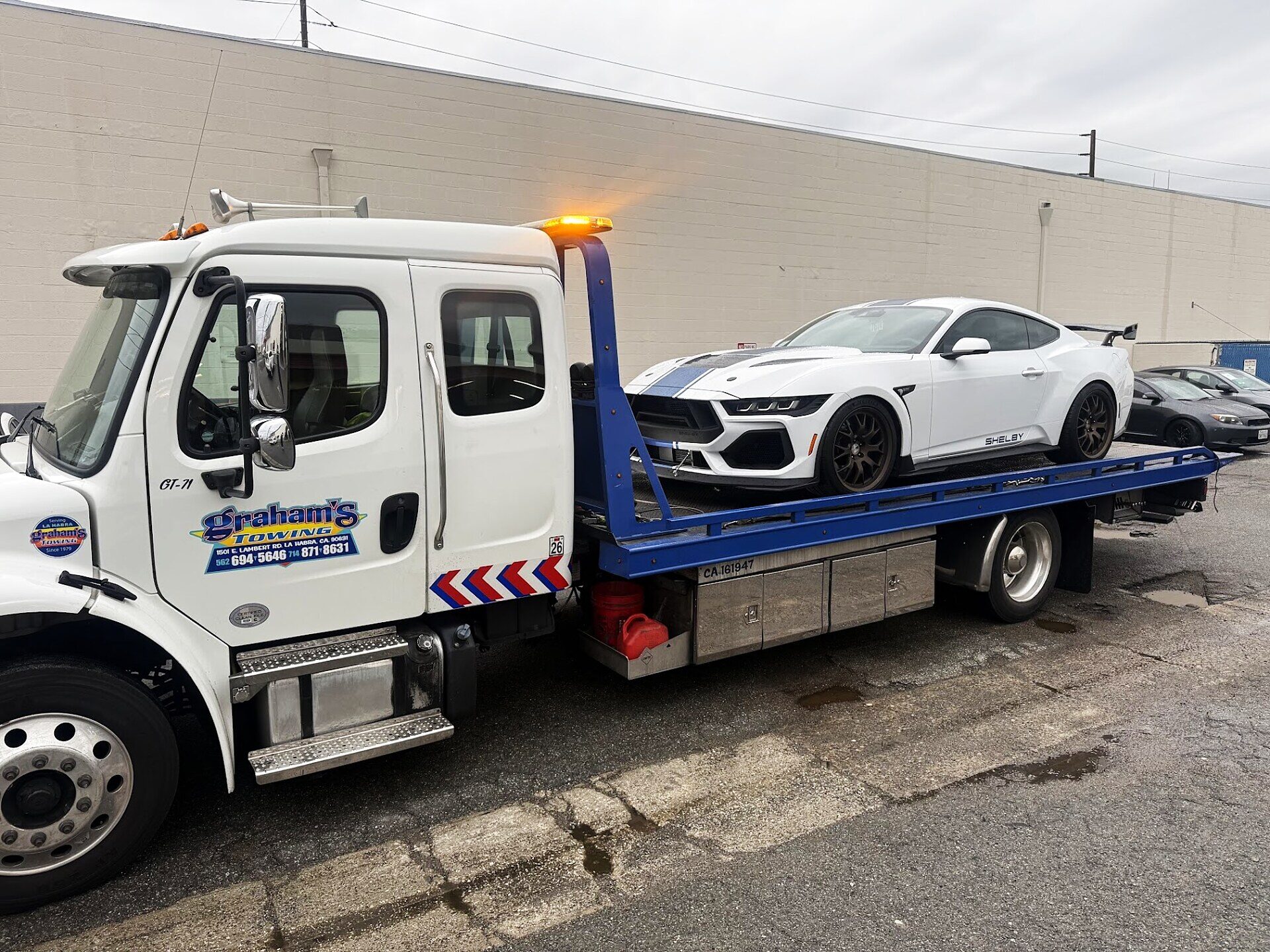 Graham's Towing flatbed loaded with a white Shelby Mustang in La Habra