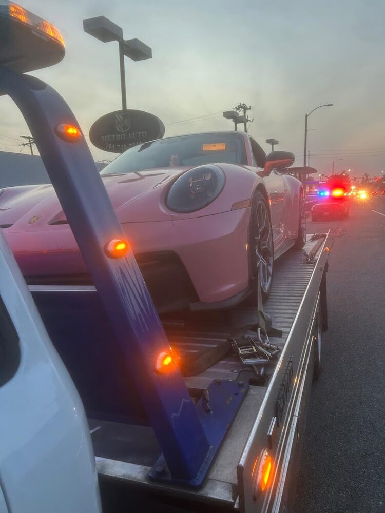 A Porsche 911 secured on a Graham's Towing flatbed at an accident scene